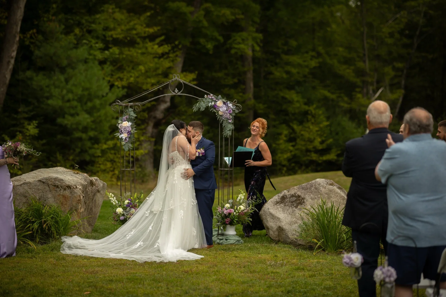 A couple kissing beneath their wedding arch at Dragonwood