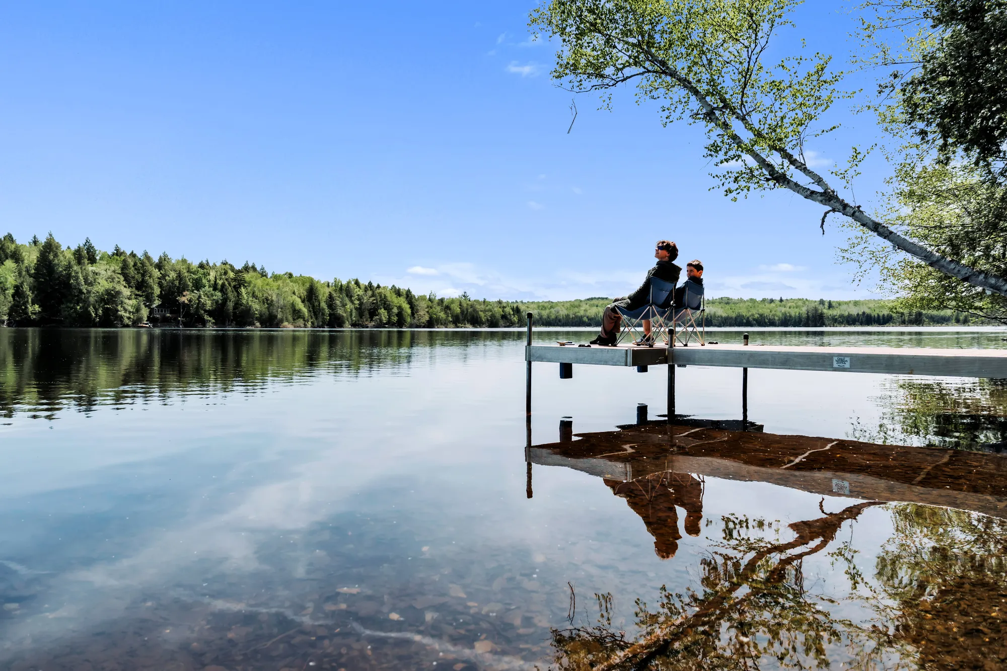 Family reflected in Manhanock Pond from the dock